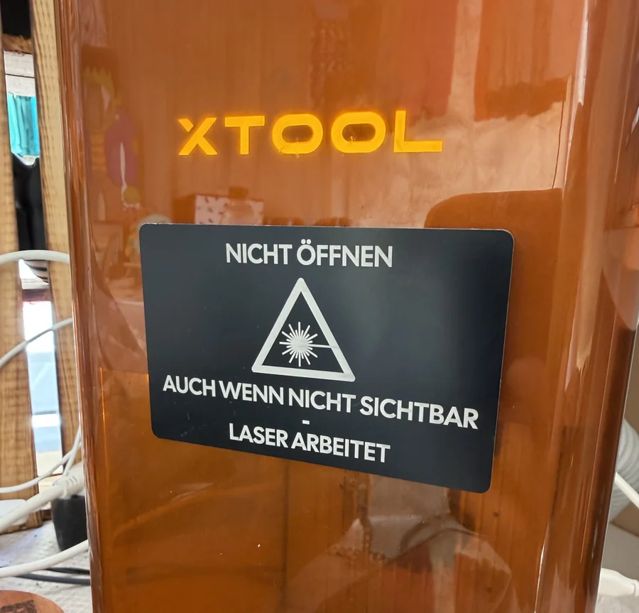 Selbst mit dem IR-Modul des xTool F2 graviertes Warnschild aus schwarz beschichteter Alukarte, direkt auf dem Gehäuse bei einem Markteinsatz